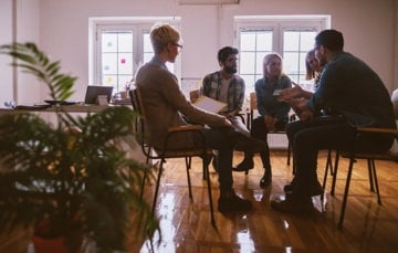 A group of young adults sitting in a room and sharing their mental health stories and experiences.